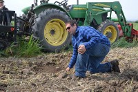 A man kneeling in a field in front of a tractor