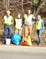 Center staff members with bags of trash and recyclable items removed from a roadside